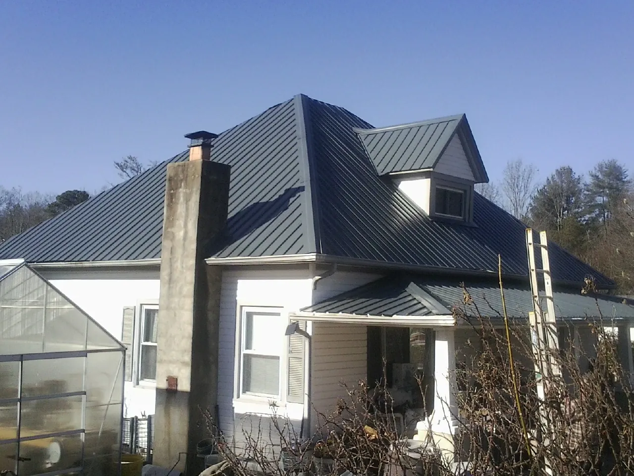 Dark blue standing seam metal roof on a white farmhouse with dormer — Slate & Tile Roof Repair by Roofing Brothers in Santa Fe Springs