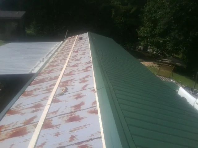 Old rusted panels beside newly installed green metal roofing — Wind Damage Roof Repair by Roofing Brothers in Santa Fe Springs
