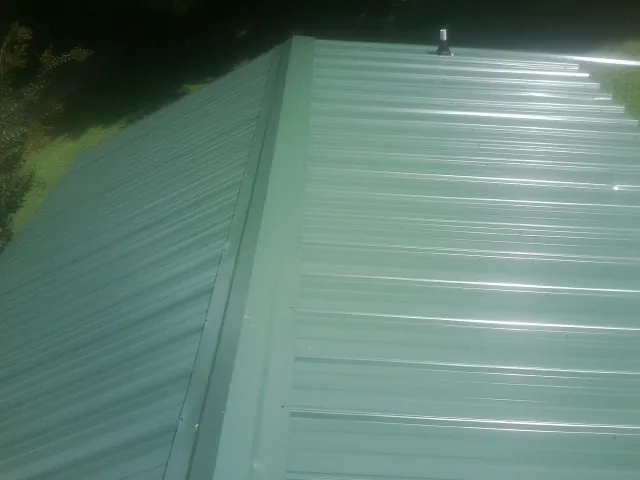 New green metal panels meeting at the ridge of a roof — Flat Roof Repair work by our crew in Santa Fe Springs