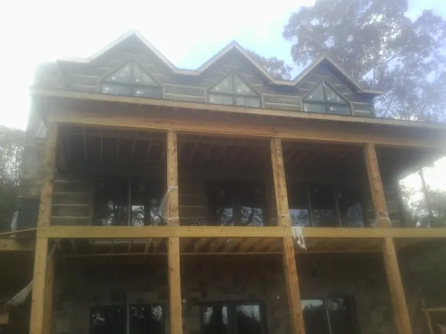 Dormers and porch framing on a large log home under construction — Roof Coating work by our crew in Santa Fe Springs