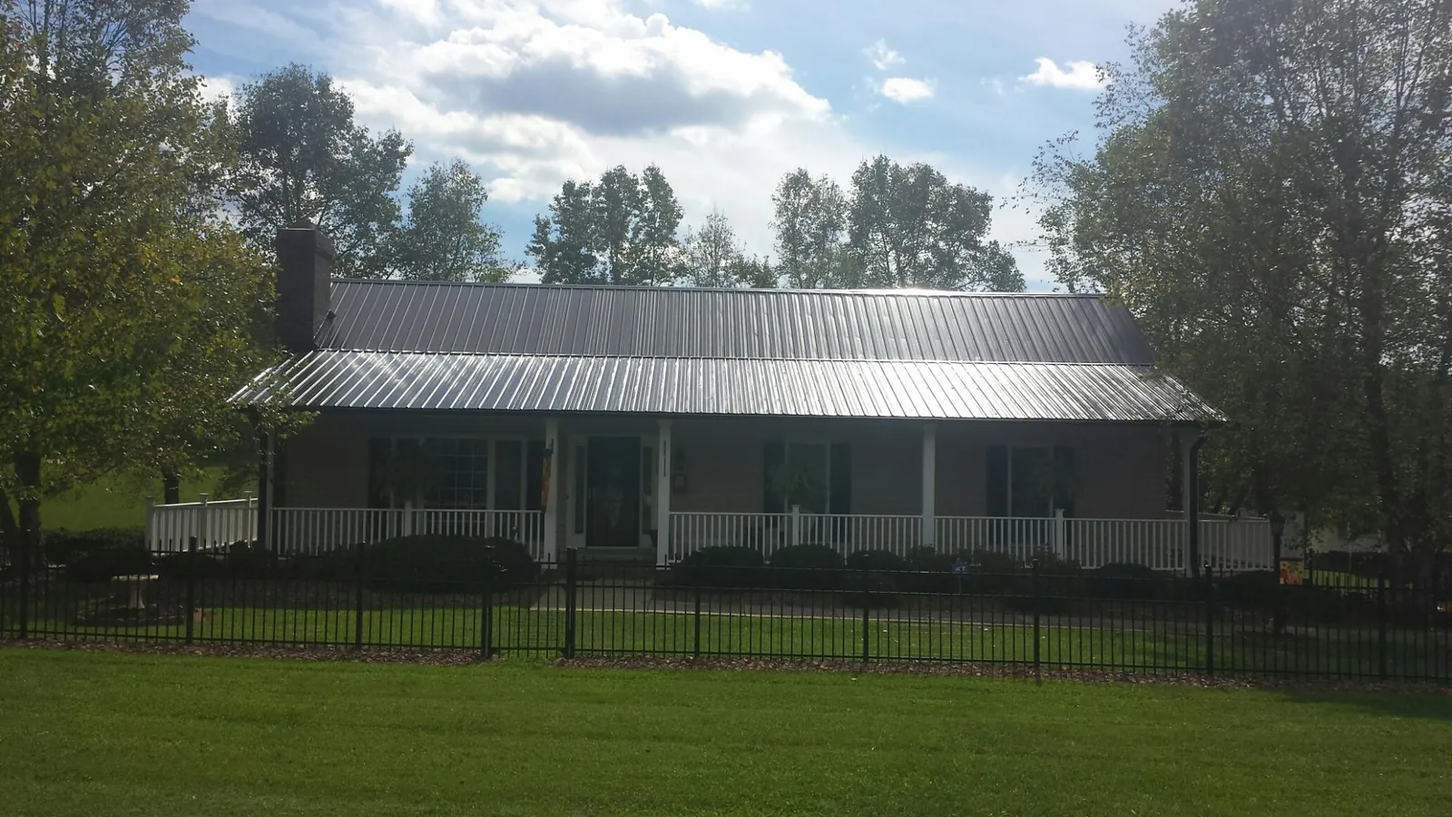 Gray metal roof on a brick ranch with a full width front porch — Gutter Guard Installation work by our crew in Santa Fe Springs