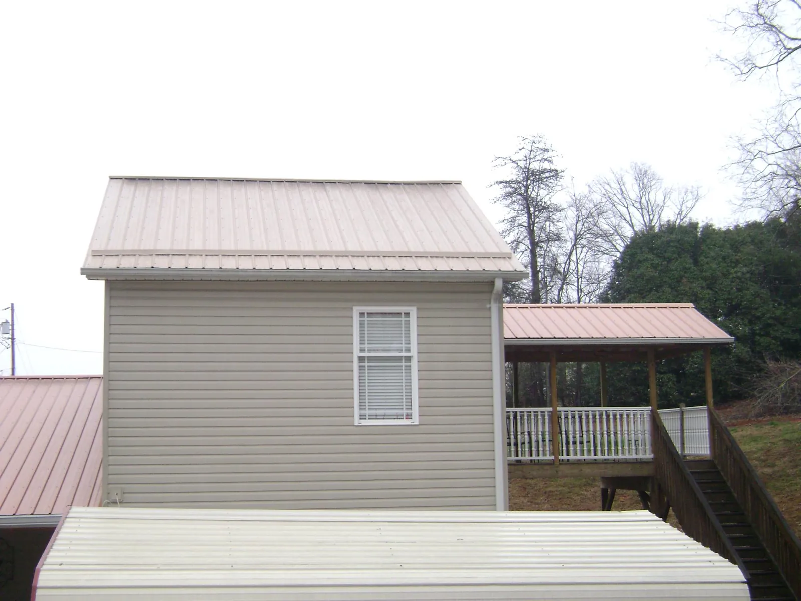 Tan metal roofs on a two story addition and attached porch, from a Roof Replacement job in Santa Fe Springs